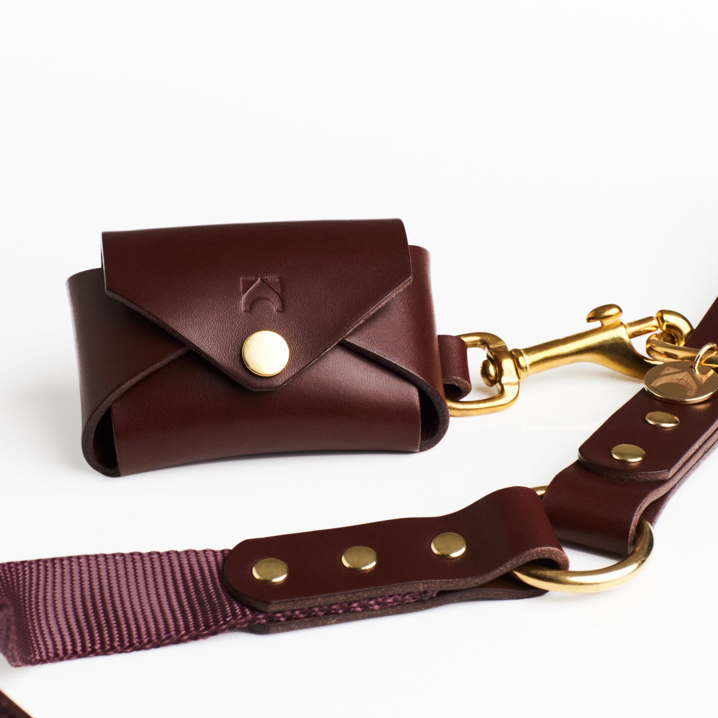 Chestnut Brown leather poop bag holder with solid brass eyelet dispenser and clip on a white background