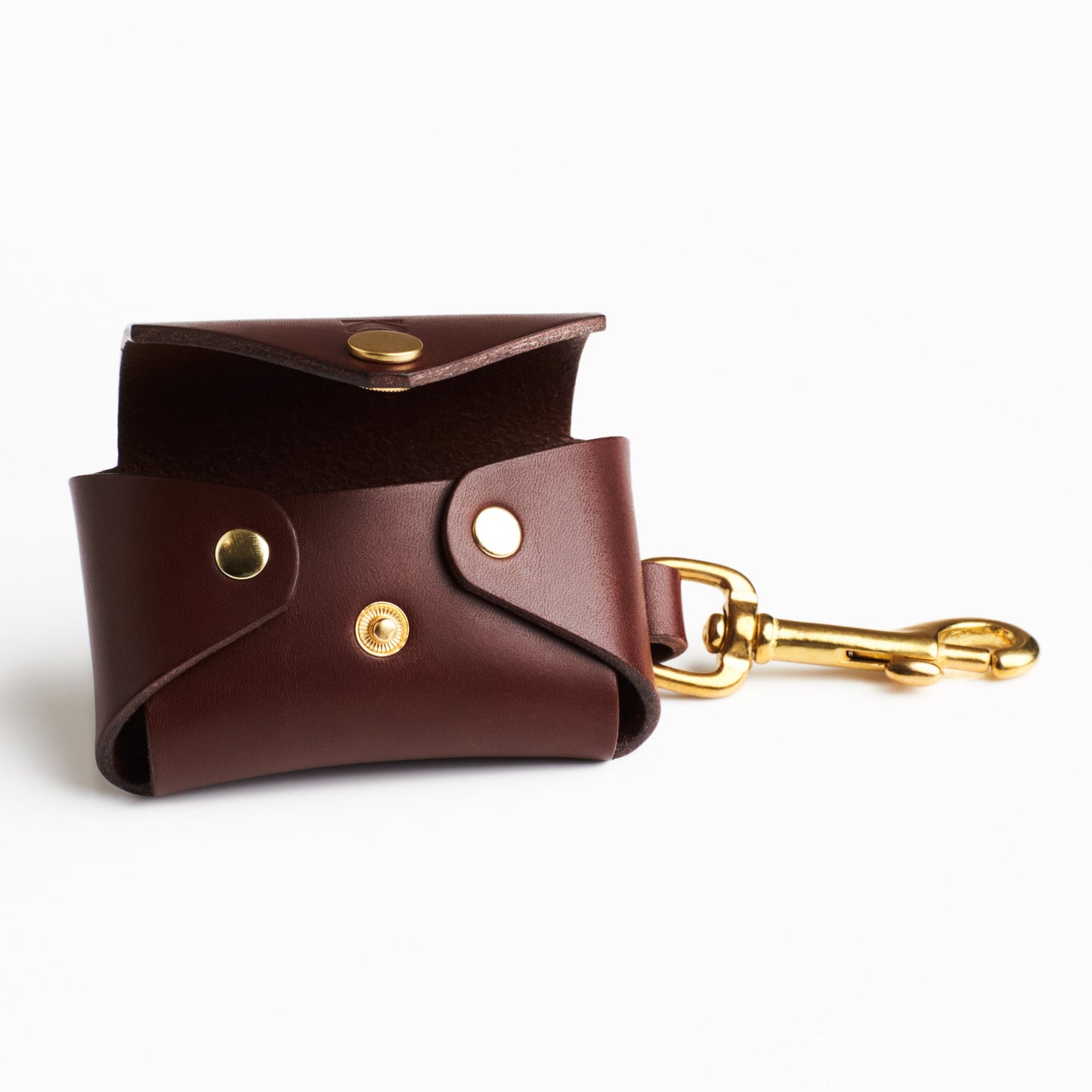 Chestnut Brown leather poop bag holder with solid brass eyelet dispenser and clip on a white background