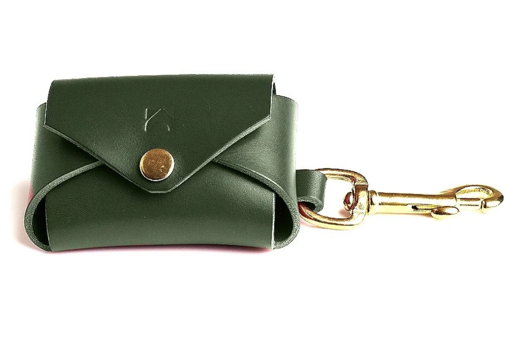 Forest Green leather poop bag holder with solid brass eyelet dispenser and clip on a white background