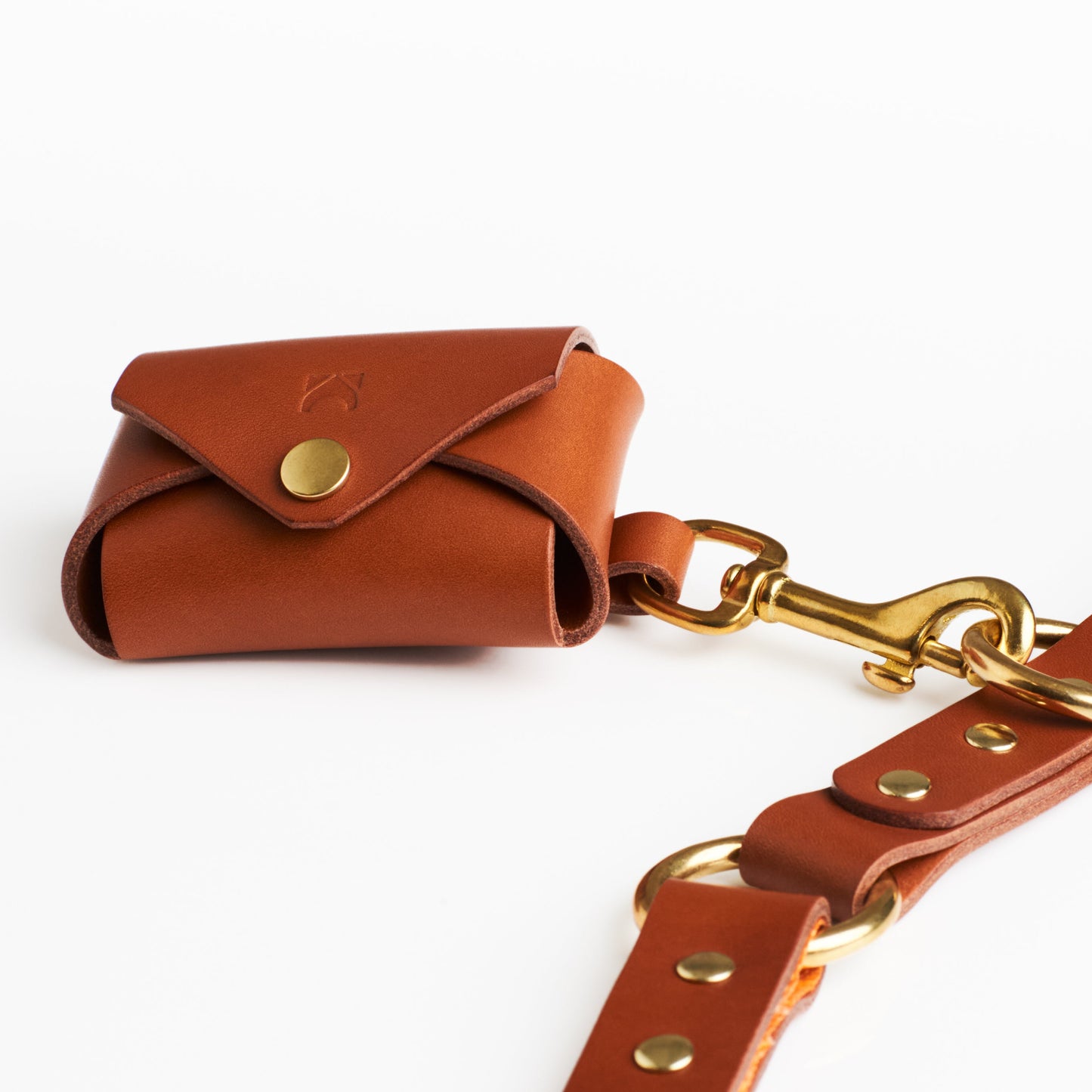 Golden Tan leather poop bag holder with solid brass eyelet dispenser and clip on a white background
