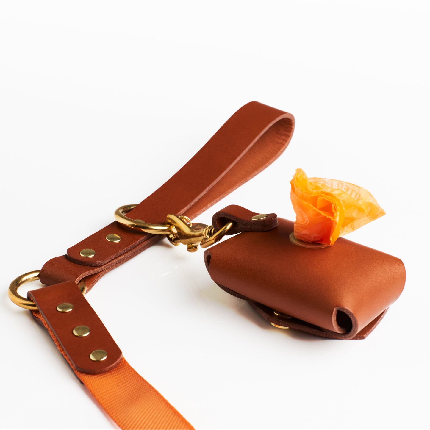 Golden Tan leather poop bag holder with solid brass eyelet dispenser and clip on a white background