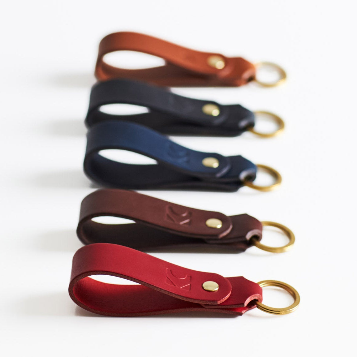 Set of five leather keyrings in different colors on a white background