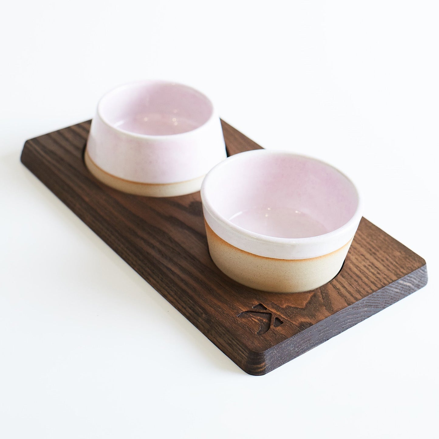 Two ceramic bowls with wooden base on a white background