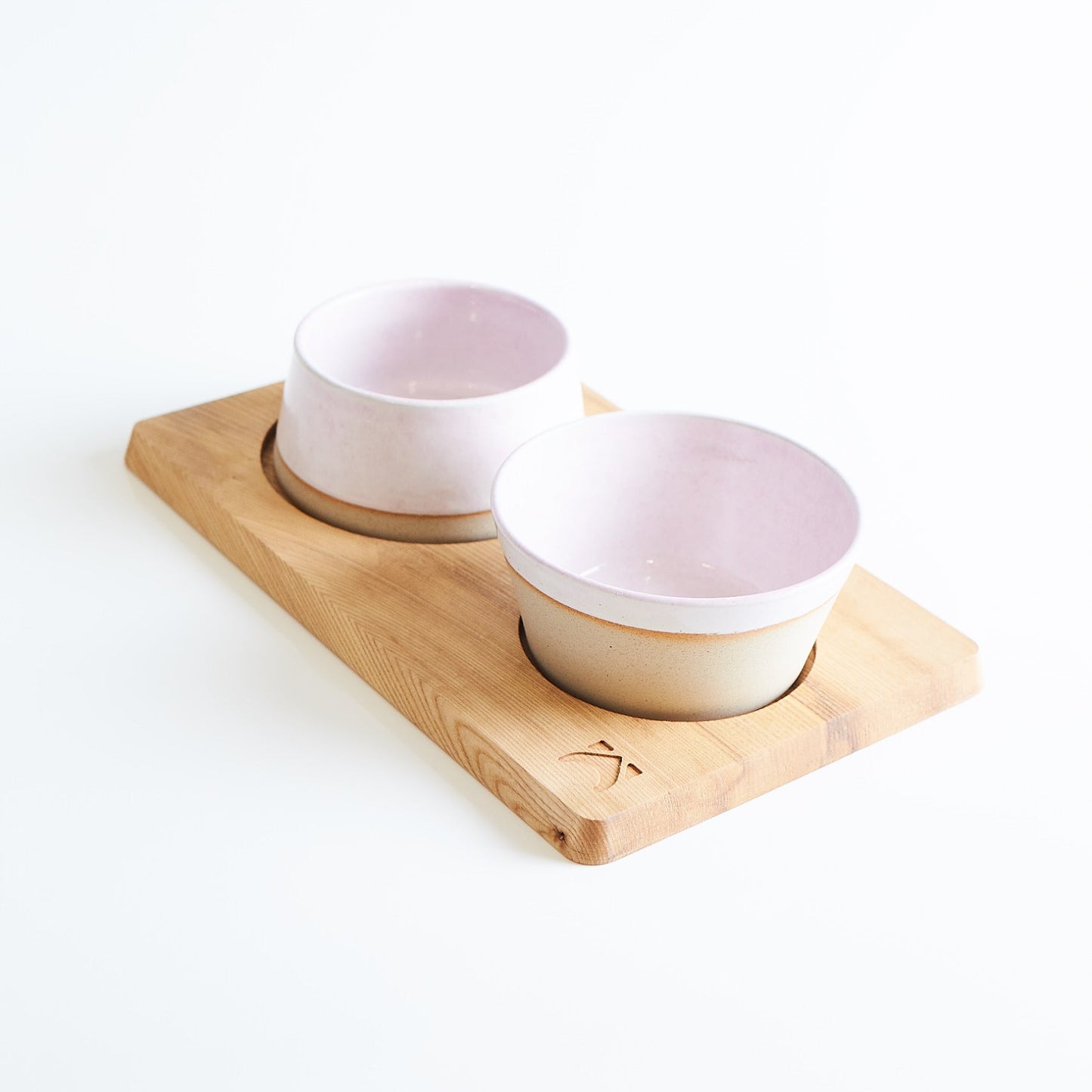 Two pink bowls on a wooden tray against a white background