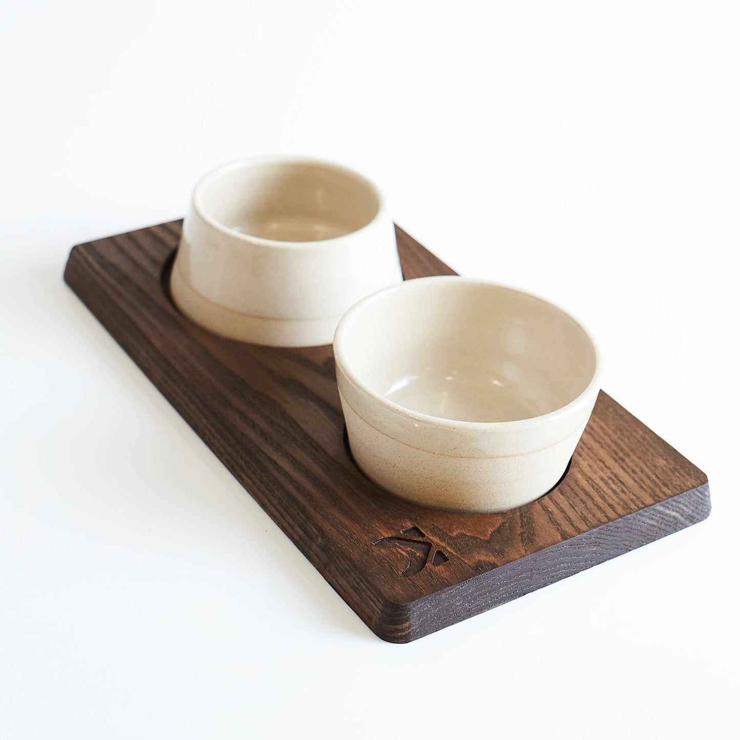 Two ceramic bowls on a wooden tray with a white background