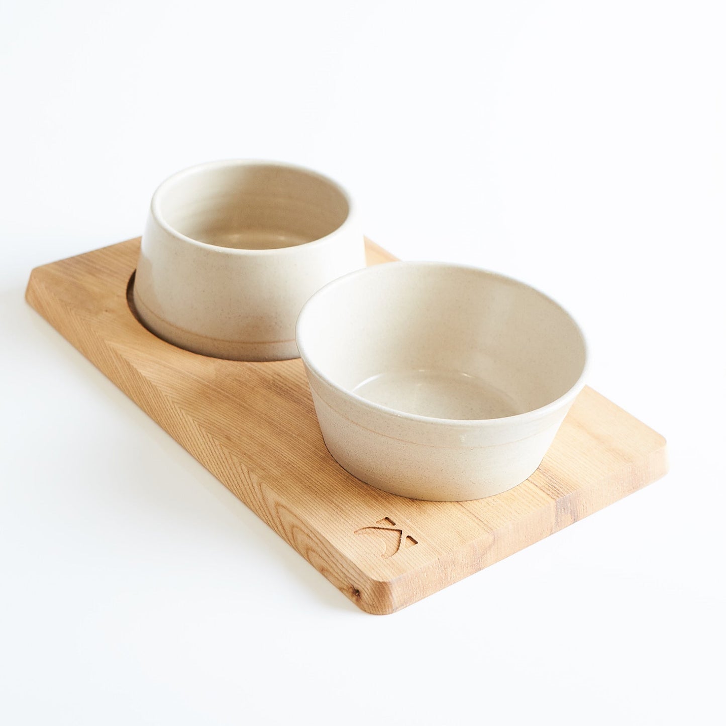 Two ceramic bowls on a wooden tray with a white background
